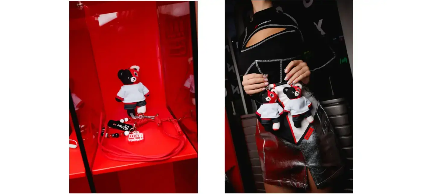 Plush bear accessories displayed on a red shelf and attached to a black-and-red outfit.